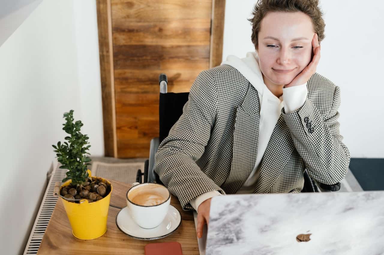 woman in wheelchair sitting at a desk using a laptop